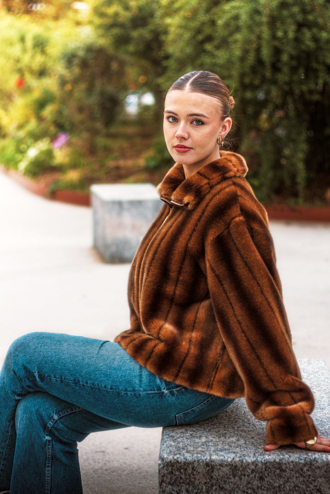 Portrait d'une jeune femme en manteau de fourrure, assise sur un banc de pierre